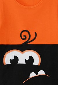Kurzarm-T-Shirt mit einem orangen oberen Abschnitt. Es hat einen schwarzen unteren Teil, gestickte Augen und geschwungene schwarze Details über den Augen.