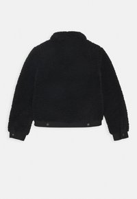 Black fleece jacket with long sleeves, snap button cuffs, and snap buttons at the waistband, shown from the back on a plain background.