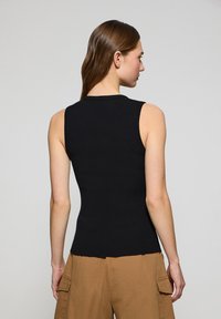 Top nero senza maniche a coste con un design aderente, mostrato da dietro, caratterizzato da una scollatura rotonda e una superficie liscia su uno sfondo chiaro.