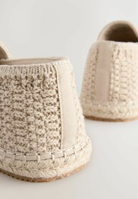 Espadrilles de color beige tejidos con un upper de tela texturizada, paneles laterales elásticos y medios suela de yute trenzado. Las suelas de goma ofrecen tracción.