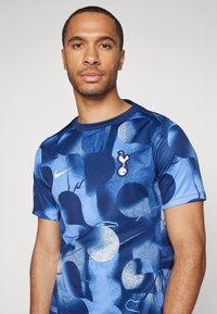 Blauwe Nike sportshirt met een abstract patroon van verschillende cirkels, voorzien van een ronde halslijn en een clublogo op de borst.