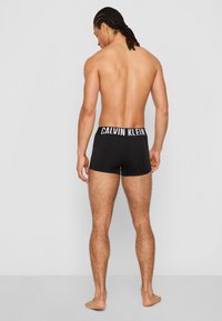 Black cotton boxer briefs with a white Calvin Klein logo waistband, fitted design, and a smooth, stretchable texture.