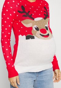 Roter Strickpullover mit einem Rentier-Motiv mit roter Nase, weißen Schneeflocken und einem weißen unteren Bereich. Gerippte Bündchen.