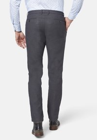 Grå linbyxor med slim fit, med bakfickor och en strukturerad yta. Bärs tillsammans med en ljusblå skjorta med prickar.