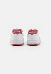 Baltas sporta apavi ar teksturētu rozā zamša papēdi un izšūtu "adidas" logotipu, ar gumijas zoli un skrāpju groziem.