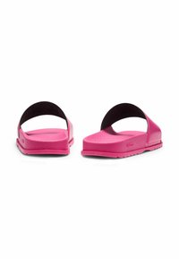 Pink slide sandals with a textured footbed, smooth straps, and a flat rubber sole. The design features minimalistic and comfortable attributes.
