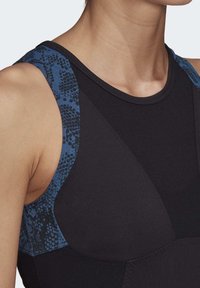 Černý sportovní top s texturovanými modrými ramenními popruhy s potiskem, kulatým výstřihem a profilovanými panely pro přiléhavý střih.