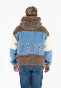 Trui in bruin, lichtblauw en roomwit. Vezelige textuur met capuchon, met grote "NAPA" logo in oranje borduursel over de rug.