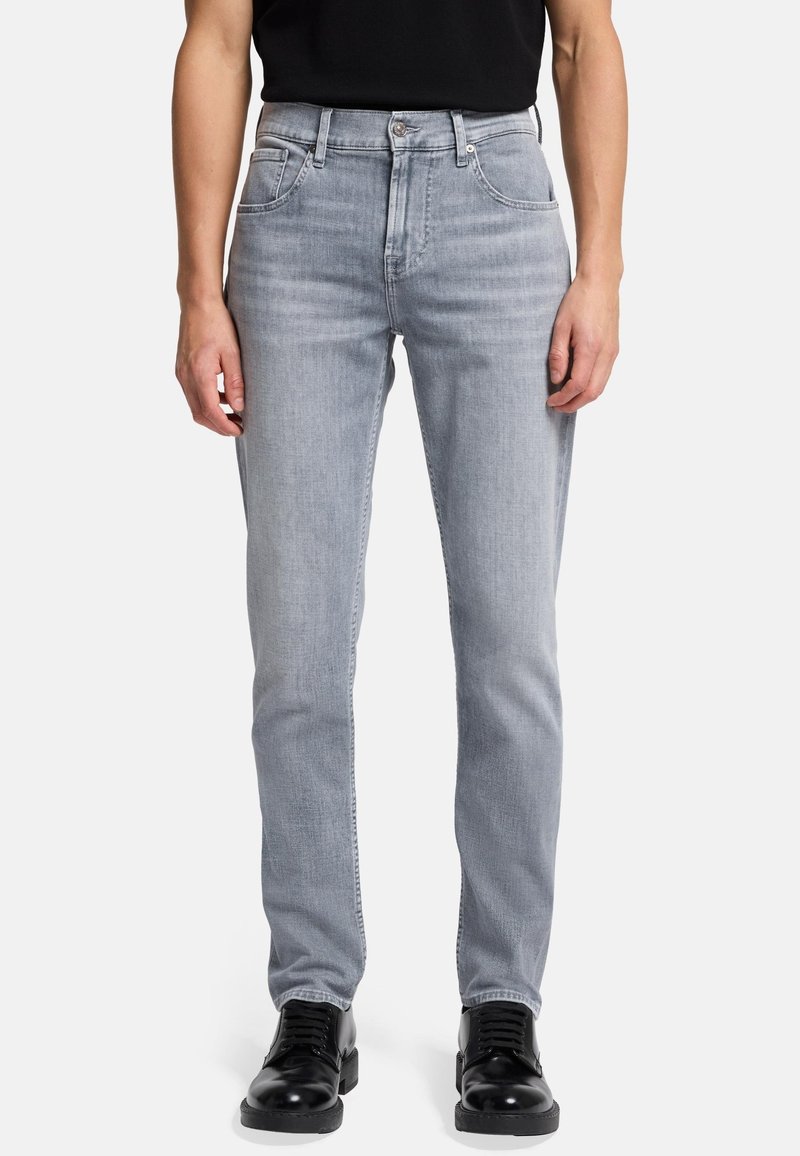 Jean en denim gris clair avec une coupe droite, cinq poches et une fermeture éclair. Présente des dégradés subtils et des détails de couture contrastée.