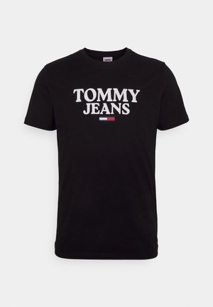 T-shirt noir à manches courtes avec texte blanc "TOMMY JEANS" et un petit logo Tommy Hilfiger rouge, blanc et bleu sous le texte.