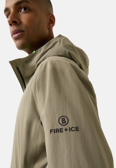 Beige lightweight jacket with a hood, notable logo "FIRE+ICE" on the sleeve, textured fabric, minimalistic design.