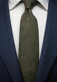 Mörkblå kavaj med en vit skjorta under, prydd med ett texturerat olivgrönt slips som har ett subtilt fiskbensmönster.