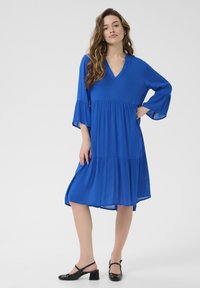 Abito blu a lunghezza ginocchio con scollatura a V, maniche a tre quarti svasate e design a strati. Realizzato in tessuto leggero, presenta una vestibilità comoda.