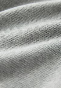 Grauer Stoff mit einer subtilen, strukturierten Oberfläche, die leichte Wellen und ein weiches Aussehen zeigt. Das Material wirkt leicht und atmungsaktiv.