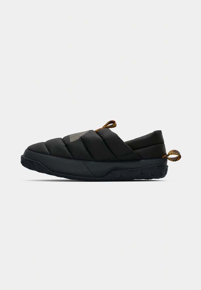 Sorte slip-on sko med quiltet stof, polstret overdel, struktureret sort sål og dekorative brune rebdetaljer ved hælen.
