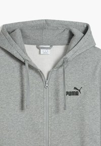 Sivá mikina na zips vyrobená z mäkkej zmesi bavlny. Má kapucňu so šnúrkou a malú čiernu Pumu logo na hrudi.