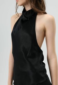 Zwarte satijnen haltertop met hoge hals en open zijkanten, met een gladde textuur en subtiele glans. Minimalistisch ontwerp, zonder zichtbare patronen.