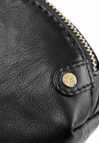 Bolso de mano de cuero negro con una superficie texturizada, herrajes en tono dorado y un detalle decorativo en la cremallera.