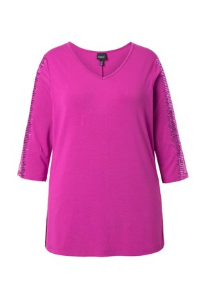 Jasnoróżowy damski top z dekoltem w serek i rękawami do łokcia, z pionowymi paskami z cekinów wzdłuż obu rękawów.