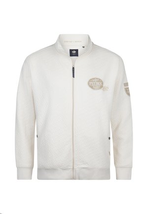 Jachetă albă matlasată cu fermoar și guler drept, având o emblema cu logo-ul pe piept și detalii accentuate pe mâneci. Croială clasică.