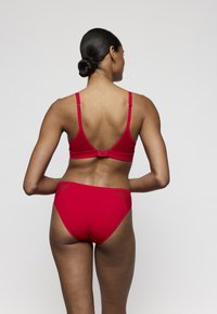Rode bikini set met een zachte, rekbare textuur. Het topje heeft verstelbare bandjes en een haaksluiting, terwijl de broekjes een hoge taille hebben.