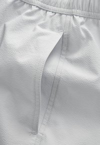 Hellgraue Shorts aus strukturiertem Stoff, mit elastischem Bund und einer Seitentasche mit einem glatten Reißverschluss.