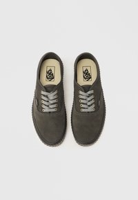Chaussures en daim gris avec semelles en caoutchouc, dotées de lacets gris et d'œillets dorés, conçues dans un style minimaliste avec une texture lisse.