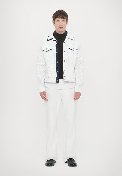 White distressed denim jacket over a black turtleneck, paired with white trousers and black shoes, against a plain white background.