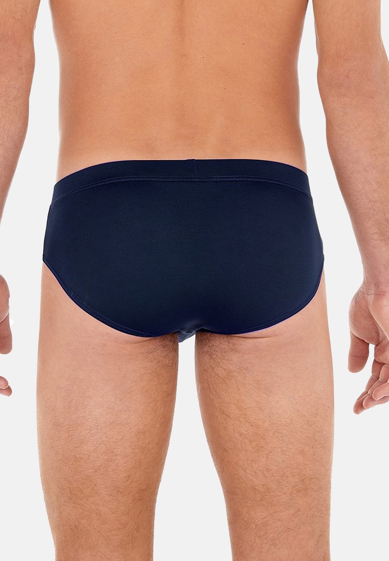 Slip da bagno blu navy realizzati in tessuto morbido, caratterizzati da una superficie liscia, una vita elastica e un design aderente per il massimo comfort.