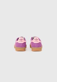Låga sneakers med en rosa och lila mocka ovandel, gummisula och en rosa hälflik med Adidas-logotyp.