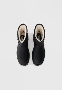 Melni potīšu zābaki ar ūdensizturīgu ārpusi, mīkstu mākslīgās kažokādas oderējumu un teksturētu gumijas zoli saķerei. Vienkāršs dizains bez papildu rotājumiem.