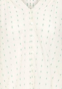Tissu couleur crème avec petits motifs floraux bleu clair et une rangée verticale de boutons blancs au centre.