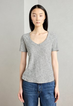 T-shirt court à manches courtes rayé gris et blanc avec un col en V, fabriqué en tissu doux, design ajusté et style décontracté, associé à un jean bleu.