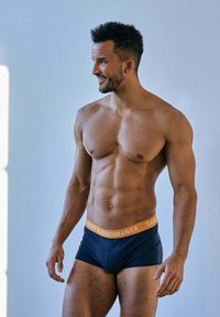 Bóxer de marinero con una cinturilla naranja. La cinturilla presenta el texto "DANISH ENDURANCE". Tela suave con un diseño ajustado.