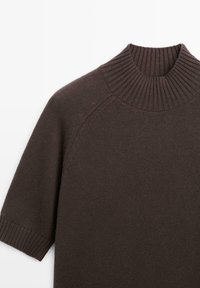 Maglione lavorato a maglia di colore marrone scuro con maniche corte, collo alto a coste e polsini a coste, disteso su uno sfondo bianco.