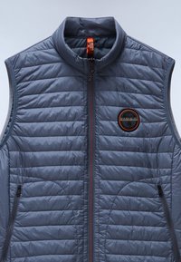 Padded gray vest with a high collar, full zip closure, and two side pockets. Features a circular logo with orange accents. Smooth texture.