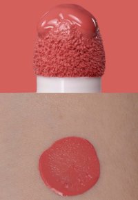 Prodotto labbra liquido color corallo con un applicatore morbido dalla punta testurizzata. Campione sulla pelle mostra una finitura liscia e cremosa con una tonalità corallo simile.