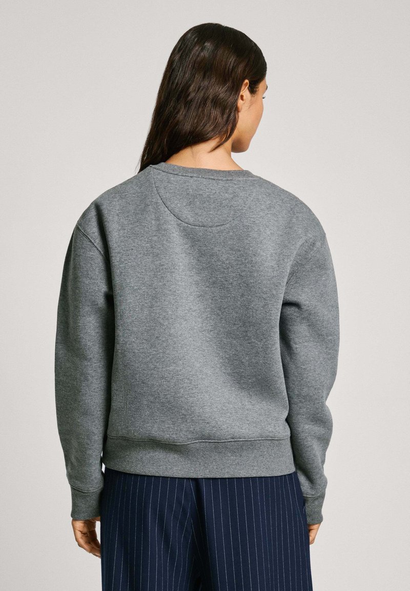 Sudadera gris de mezcla de algodón, con un cuello redondo y puños acanalados, mostrada desde la parte posterior con una textura suave.