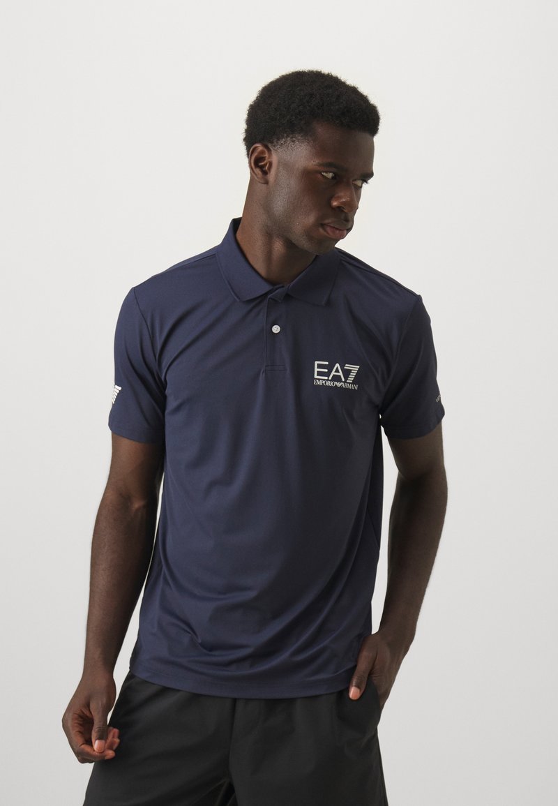 Navy polo shirt made of smooth, breathable fabric. Features a collar, short sleeves, and an EA7 logo embroidered on the chest.