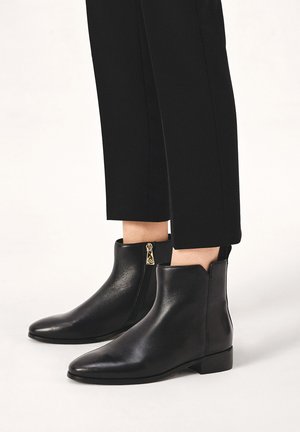 Black leather ankle boots with pointed toes, side zippers, and a low block heel. Smooth texture with no visible patterns.