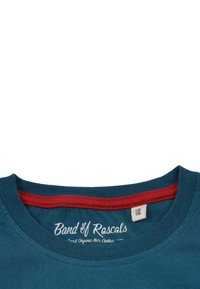 Teal vävda T-shirt med en röd innerkrage, som har vit logotyptext "Band of Rascals" och storleksmärke inuti kragen.