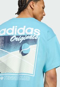 Tirkizna pamučna majica s grafičkim dizajnom teniskog terena, lopte i natpisom "adidas Originals 1972 TENNISCLUB" u bijeloj boji.
