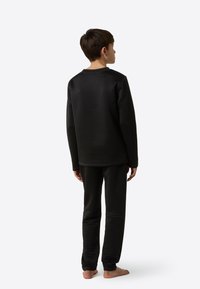 Čierna termo sada pre deti s textúrovaným vzorom. Dlhý rukáv mikiny a zodpovedajúce nohavice, obe s voľným strihom a rebrovanými manžetami.