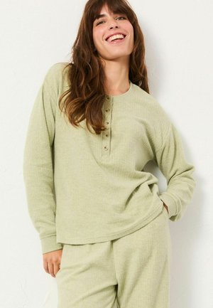 Light green, textured long-sleeve top with a crew neck and a button placket, paired with matching pants, depicted in a relaxed pose.