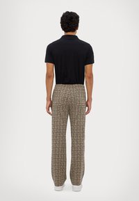 Mustapolo-paita yhdistettynä monivärisiin ruudullisiin housuihin. Housuissa on rento istuvuus, joustava vyötärö ja sivutaskut.