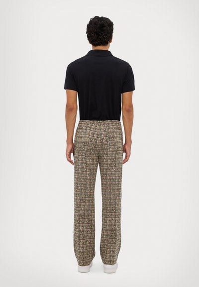 Black polo shirt paired with multi-colored plaid trousers. Trousers feature a relaxed fit, elastic waistband, and side pockets.