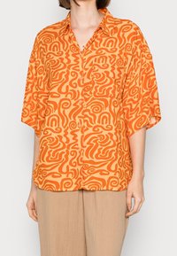 Korte mouwen oranje shirt met abstracte witte patronen, knoopsluiting aan de voorkant en een enkele borstzak. Lichtgewicht stof met een ontspannen pasvorm.