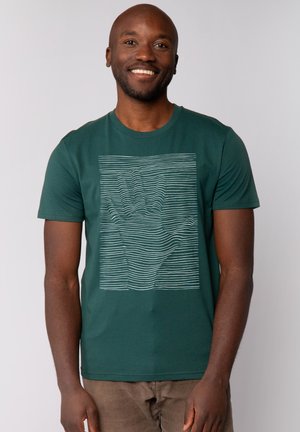 Grünes Baumwoll-T-Shirt mit einem weißen linearen Handgrafik auf der Vorderseite. Kurze Ärmel und ein Rundhalsausschnitt. Weicher Stoff.