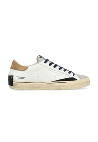 Sneaker bianco in pelle con lacci blu navy, dettagli color cammello e punta testurizzata. Presenta una striscia laterale nera e una suola invecchiata con dettagli del logo.