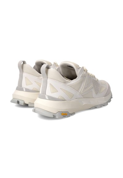 Baskets de couleur crème avec un dessus texturé, des découpes géométriques et une épaisse semelle blanche. Présente un logo Vibram sur la semelle extérieure.